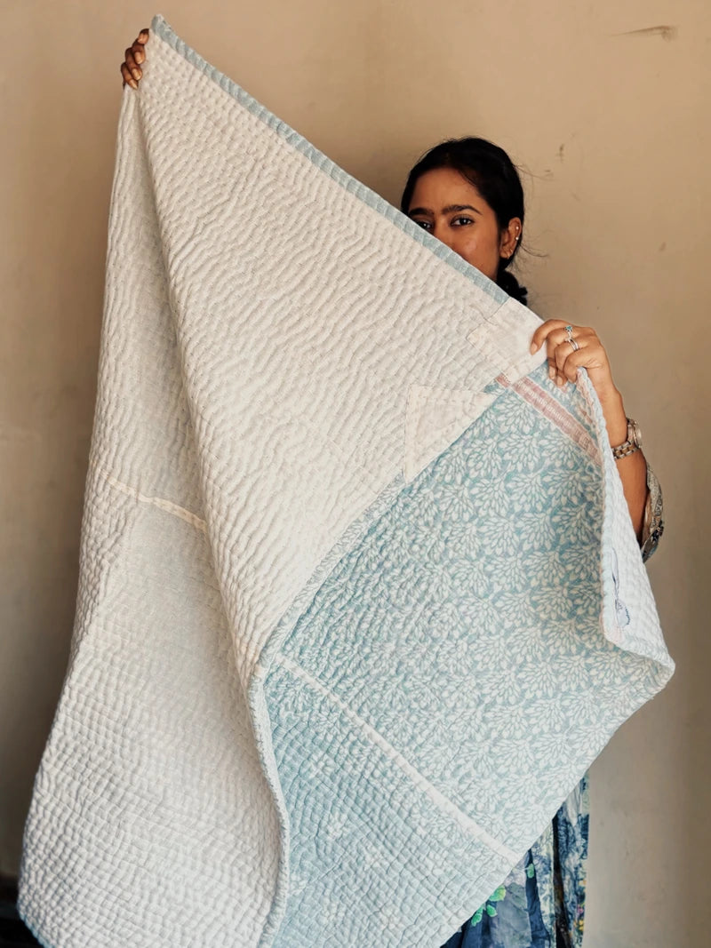 Padded kantha quilt with subtle pattern of traditional sari cloth through sheer white overlay